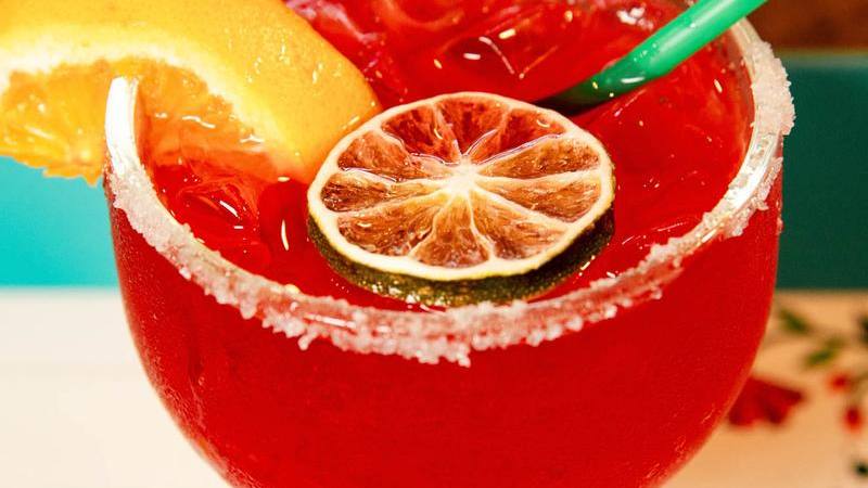 A red margarita with a lime wheel and a salted rim