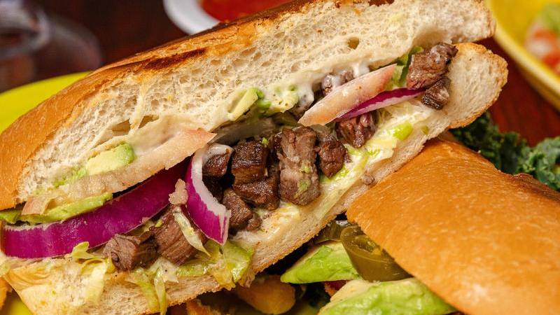 A torta stacked with steak, avocado and onion, with fries