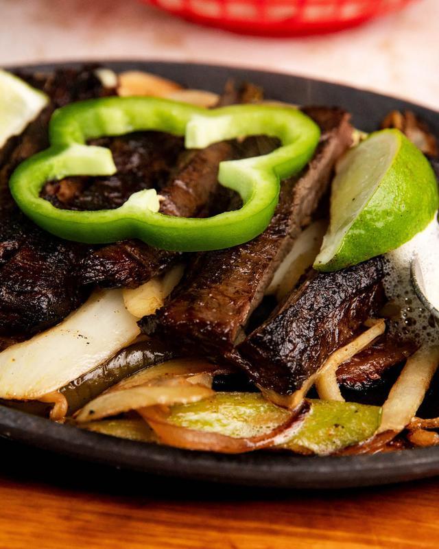 Beef fajitas on a cast iron skillet with peppers and onion