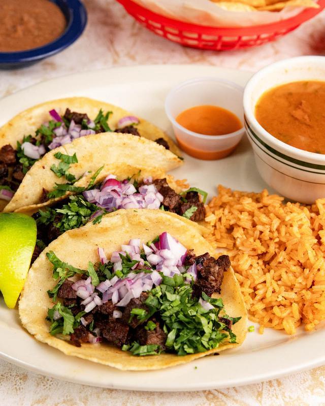 Street tacos with lime, rice and a cup of charro beans