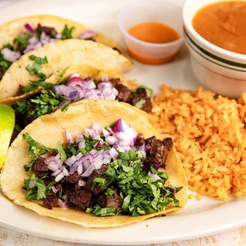Three street tacos with steak, cilantro and onion, rice on the side