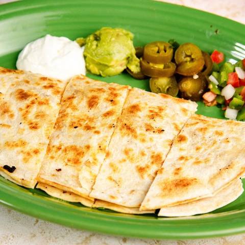 A grilled quesadilla with guacamole, jalapenos and pico de gallo