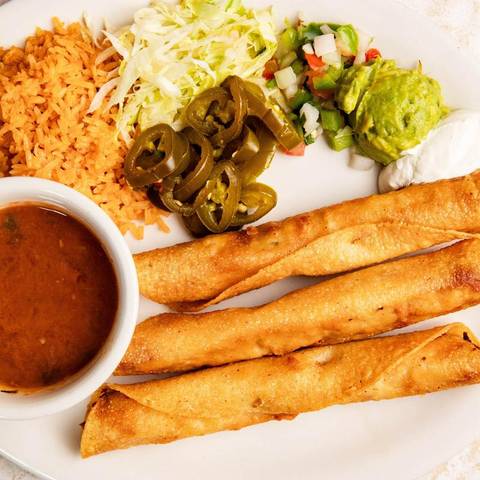 Golden flautas with a cup of salsa and jalapenos