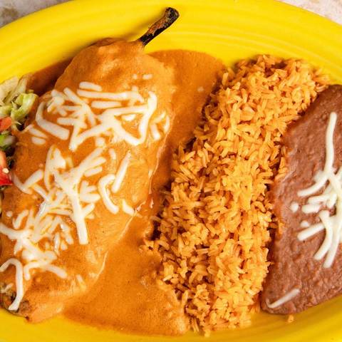 A chile relleno under a creamy tomato sauce with rice
