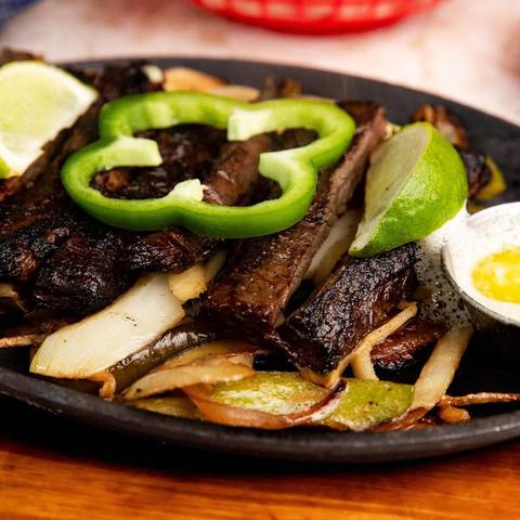 Beef fajitas on a cast iron skillet with peppers and onion
