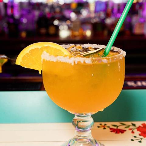 A frozen orange margarita with an orange slice