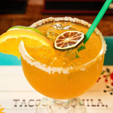 A golden margarita with orange and dried lime
