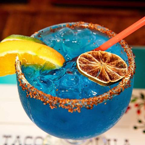 A blue margarita with a dried orange slice