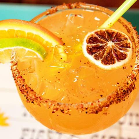 An orange margarita with a dried orange wheel